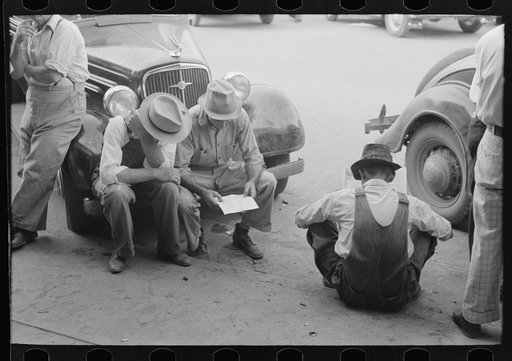 Farmers sitting on curb and bumpers of car, Saturday afternoon, Steele, Missouri