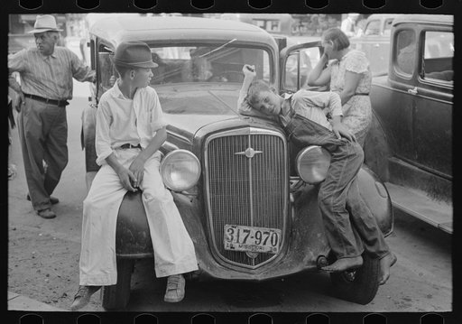 Children sitting on fenders of car, Steele, Missouri