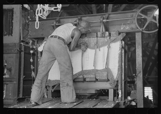 Putting steel straps in place to hold pressed cotton after pressure has been removed, Lehi, Arkansas cotton gin
