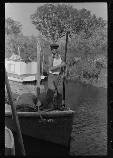 Poling oyster boat to dock in canal, Olga, Louisiana