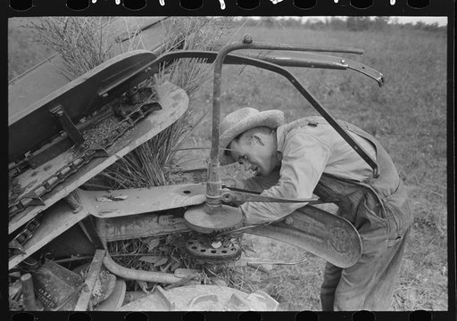 Member of Lake Dick Cooperative Association repairing mowing machine, Arkansas