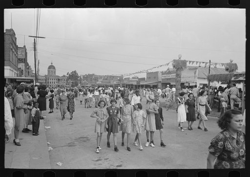 After the parade is over people follow the line of it, walking down the middle of the street, National Rice Festival, Crowley, Louisiana
