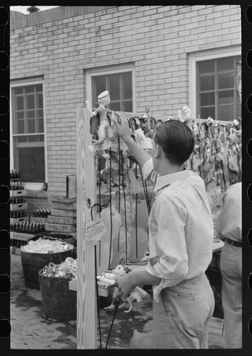 Untitled photo, possibly related to: Concessionaire placing doll canes in rack, National Rice Festival, Crowley, Louisiana