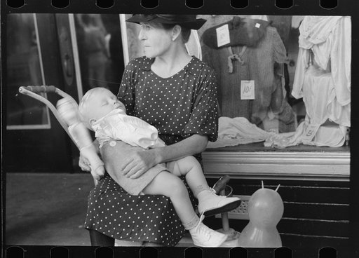 Untitled photo, possibly related to: Woman with child in front of store during National Rice Festival, Crowley, Louisiana