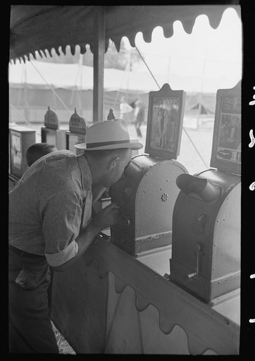 Man looking through penny peep show, state fair, Donaldsonville, Louisiana