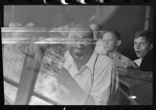 Untitled photo, possibly related to: Man chewing piece of snake which he has just bitten off, state fair sideshow, Donaldsonville, Louisiana