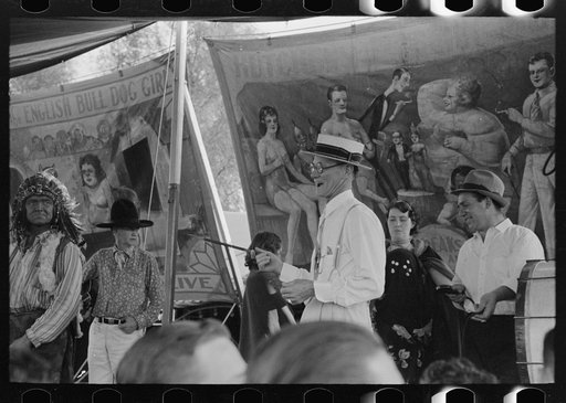 Barker at sideshow with performers, state fair, Donaldsonville, Louisiana