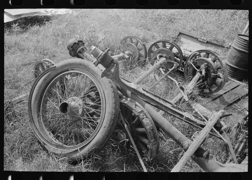 Old auto wheel and tire with front axle assemblies, near Abbeville, Louisiana, junkyard