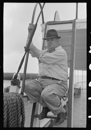 First mate of packet boat El Rito sitting on ladder to boat deck, Louisiana