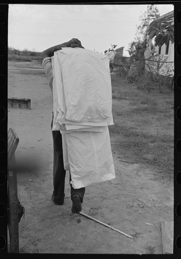 Carrying dry cleaned articles to store from boat, Burrwood. Articles to be cleaned must be sent to New Orleans