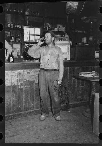 Native of Olga, Louisiana drinking at the bar. Note the branch of tree used as a mosquito switch