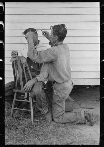 Cajun sugarcane farmer cutting hair of neighboring farmer near New Iberia, Louisiana