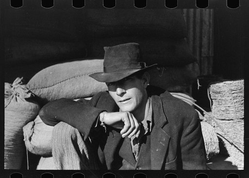 Untitled photo, possibly related to: Man resting on sack of grain near barbed wire, New Roads, Louisiana