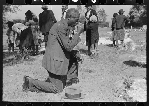 Negro crossing himself and praying over grave of relative in cemetery, All Saints' Day, New Roads, Louisiana