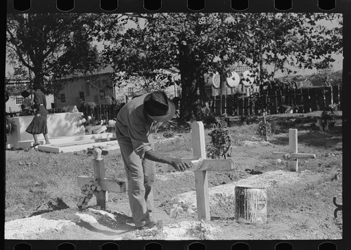 Painting grave marker in cemetery, All Saints' Day in New Roads, Louisiana