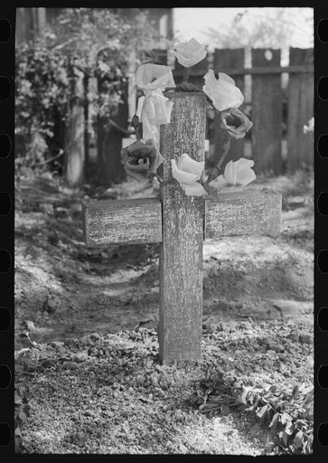 Decorated headstone in cemetery, New Roads, Louisiana on All Saints' Day. Artificial flowers are made of paper