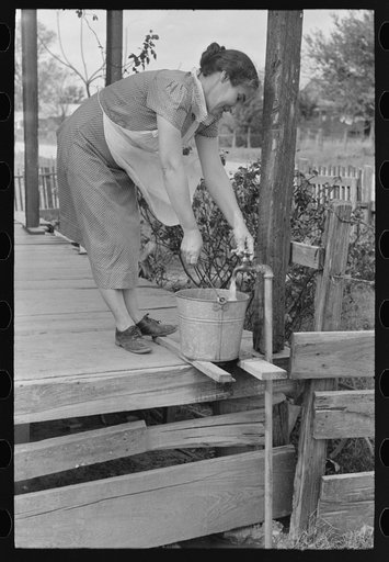 Wife of tenant farmer who will participate under tenant purchase drawing water near Morganza, Louisiana. While they live in the outskirts of a city and have access to city facilities, this is the only tap in the house