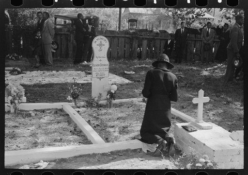 Negro women praying at grave of son in cemetery at New Roads, Louisiana on All Saints' Day