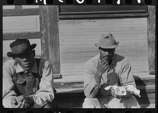 Untitled photo, possibly related to: Negroes sitting on foot of the T&P (Texas and Pacific) railroad station, New Roads, Louisiana. Note frequency of train operations