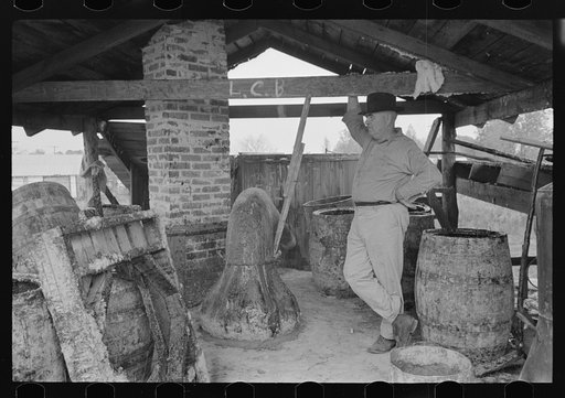 Owner atop his turpentine still. Goosneck runs from the still to the condenser coils where vapors are chilled. State Line, Mississippi