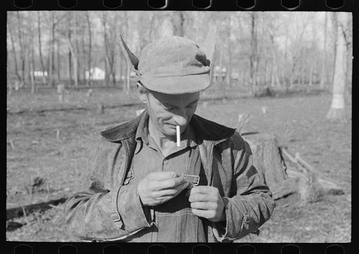 Farmer of Chicot Farms, Arkansas striking match on button of overalls