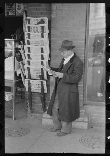 Reading newspaper in front of newsstore, Laurel, Mississippi