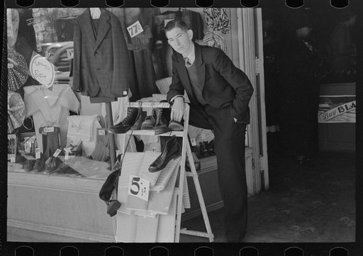 Salesman standing in front of store on Saturday afternoon, Laurel, Mississippi