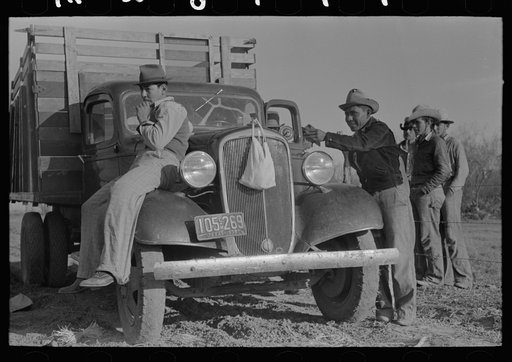 Mexican carrot workers around labor contractor's truck in field near Santa Maria, Texas