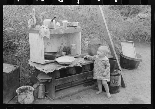 Untitled photo, possibly related to: Child of migrant worker sitting on bed in tent home of cotton picking sacks, Harlingen, Texas