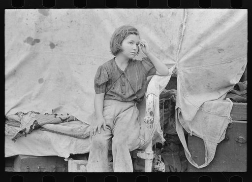 Child of migrant worker sitting on bed in tent home of cotton picking sacks, Harlingen, Texas