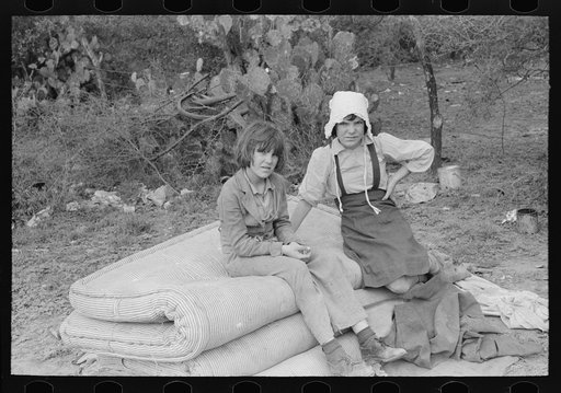 Children of white migrants from west Texas sitting on mattresses just unloaded from trailer. Harlingen, Texas