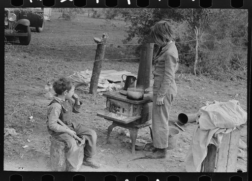 Untitled photo, possibly related to: Child of white migrant adding water to boiling beans on stove which was set up immediately after reaching camping grounds near Harlingen, Texas