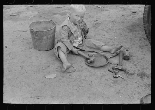 Child of white migrant worker playing with automobile tools near Harlingen, Texas
