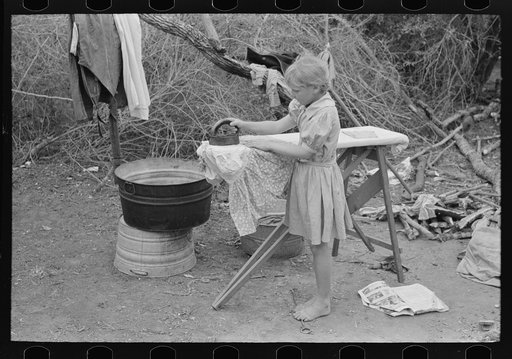 Child of white migrant worker ironing in camp near Harlingen, Texas