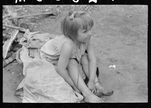 Child of white migrant worker sitting on cotton pickers' sacks near Harlingen, Texas