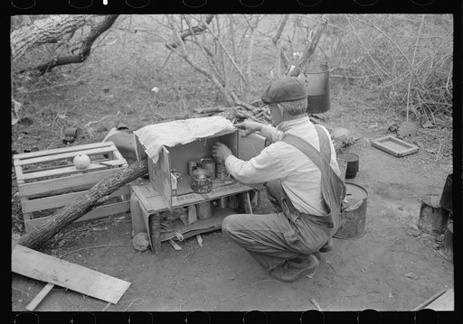Untitled photo, possibly related to: White migrant worker living in camp with two other men, working on lean-to which is to be his sleeping quarters. Near Harlingen, Texas