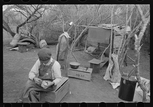 White migrant worker living in camp with two other migrant men. His sleeping quarters and all worldly possession are to be seen in background. Harlingen, Texas