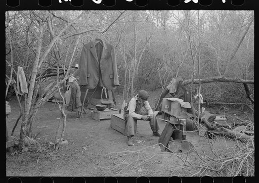 White migrant worker living in camp with two other migrant men. His sleeping quarters and all worldly possession are to be seen in background. Harlingen, Texas