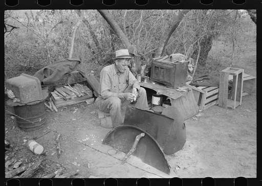 White migrant sitting in front of his fire in camp near Harlingen, Texas. He is one of the three traveling separately but who have set up camp together near Harlingen, Texas. Each cooks and eats alone. They were attracted to the lower valley by reports of plentiful work but have been unable to compe