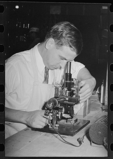 Chemist running microscopic test on sweet potato starch at plant, Laurel, Mississippi