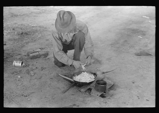 Migrant worker cooking meal over campfire, Edinburg, Texas