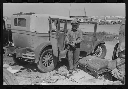 Migrant auto wrecker in front of car which he will dismantle, Corpus Christi, Texas