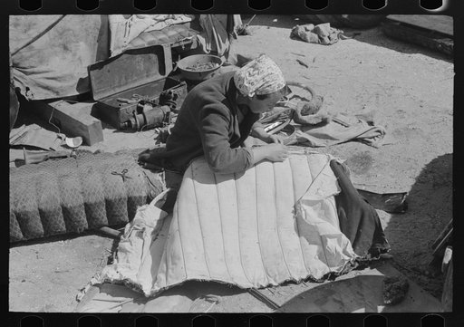 Wife of migrant auto wrecker sewing seat cushion of wrecked auto, Corpus Christi, Texas