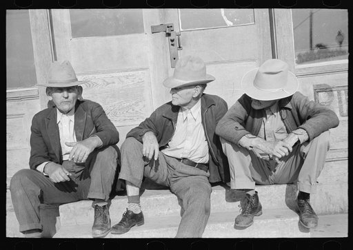 Residents of Crystal City, Texas sitting on steps of store