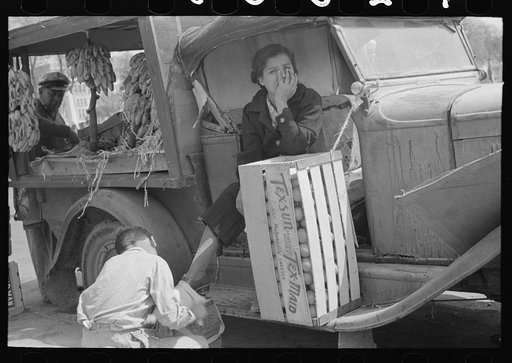 Wife of fruit vendor having shoes shined at market in San Antonio, Texas