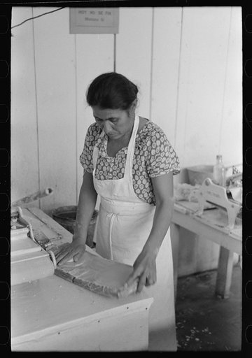 Mexican woman flattening and shaping tortillas between two boards hinged together, San Antonio, Texas
