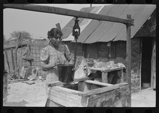 Untitled photo, possibly related to: Mexican woman drawing a bucket of water from backyard well, San Antonio, Texas