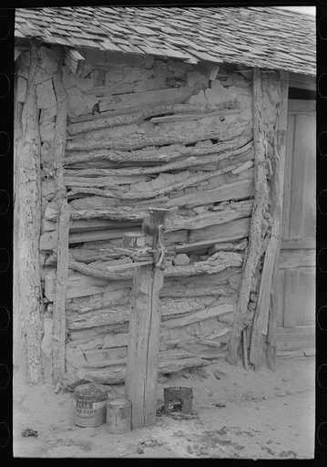 Detail of Mexican house made of sticks and mud. Corn grinder is on post in front. Crystal City, Texas