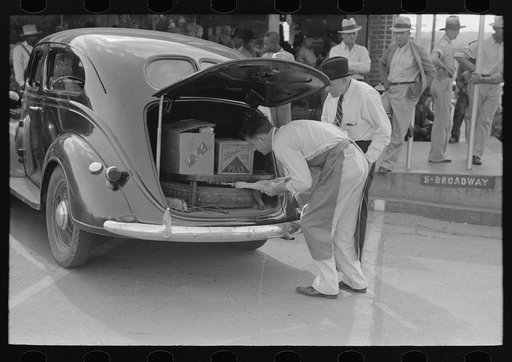 Grocery clerk putting broom and other supplies in back of automobile, Saturday afternoon, San Augustine, Texas