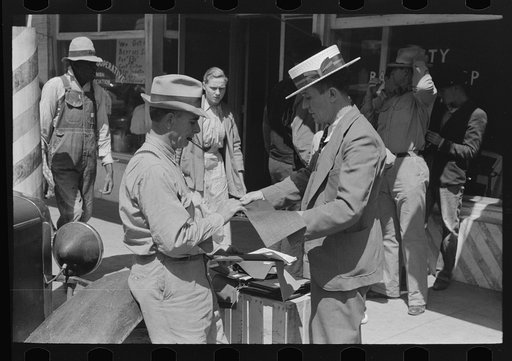 Salesman displaying sample of suit material to farmer, Hammond, Louisiana